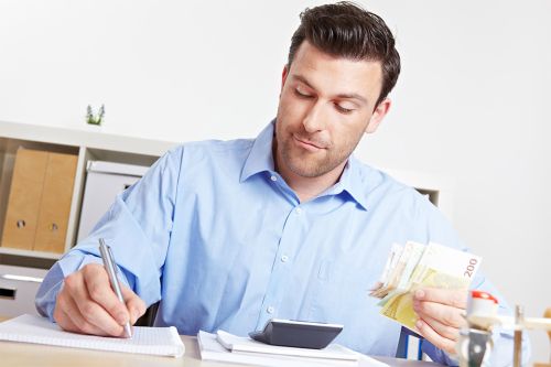Foto: Mann mit Stift und Geldscheinen in den Händen